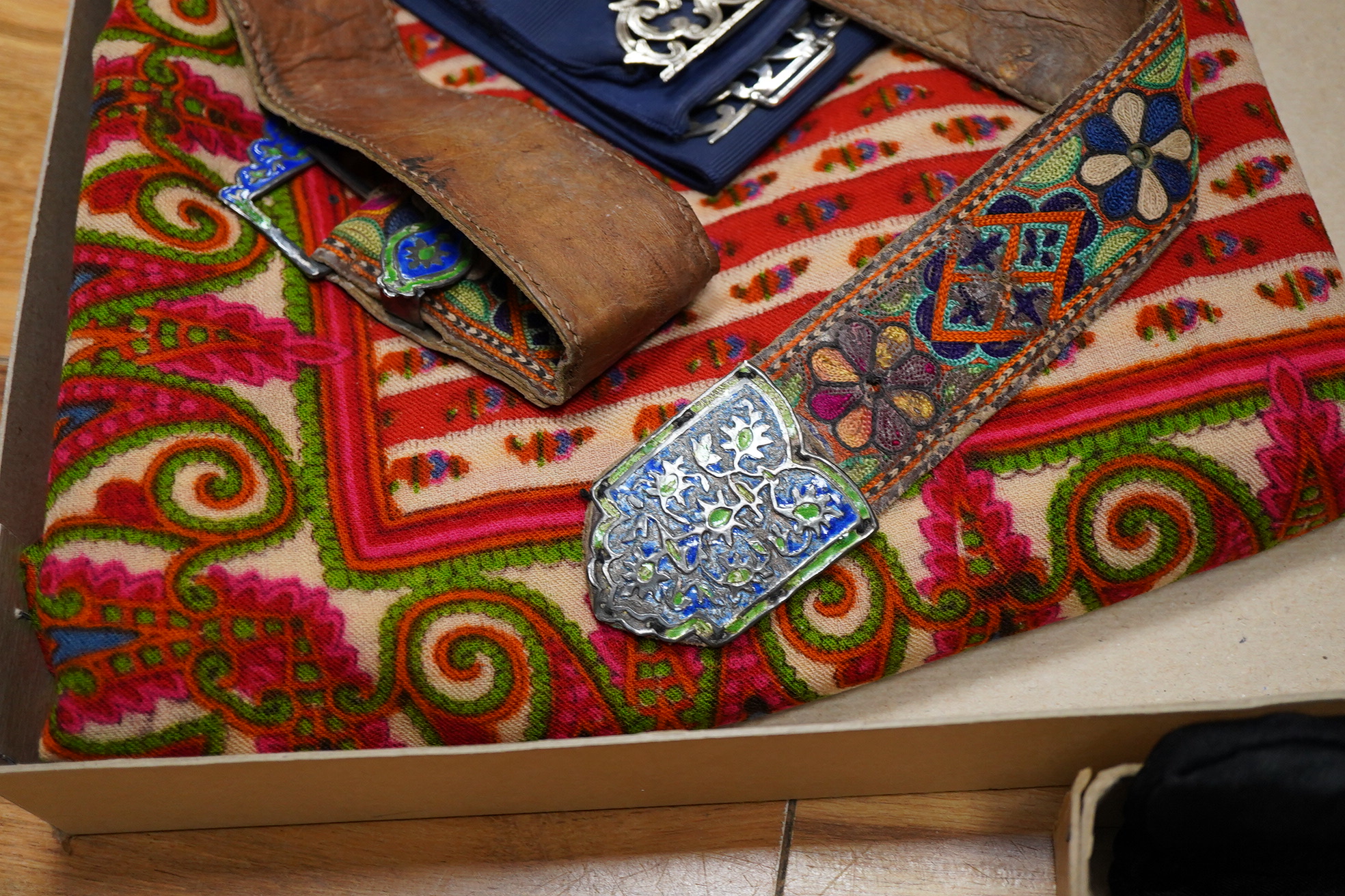 A collection of textiles: a ribbon work hankie and pyjama case, a metalwork collar, a coloured printed shawl, a nurses belt and embroidered belt, an advertising Guggenheim Bilbau hankie etc (10). Hankie case 22cm square.